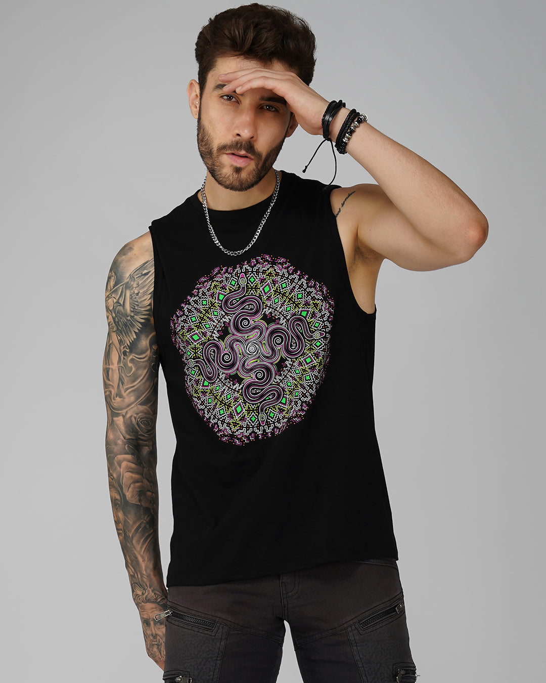 A male model wearing a black tank top with a geometric cut sleeve featuring multicolor patterns.