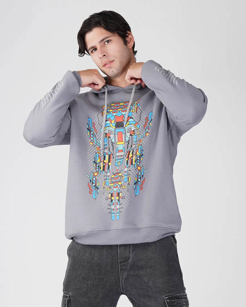Person wearing a gray hoodie with a colorful geometric design on a white background