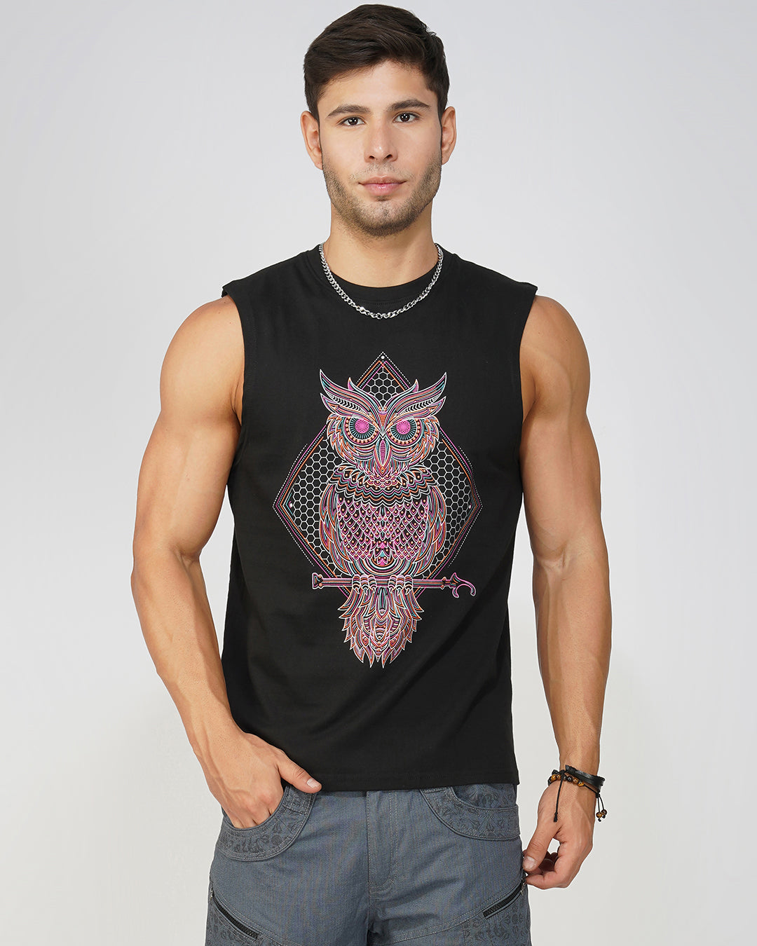 Man wearing a black sleeveless shirt with a colorful owl design on a plain background