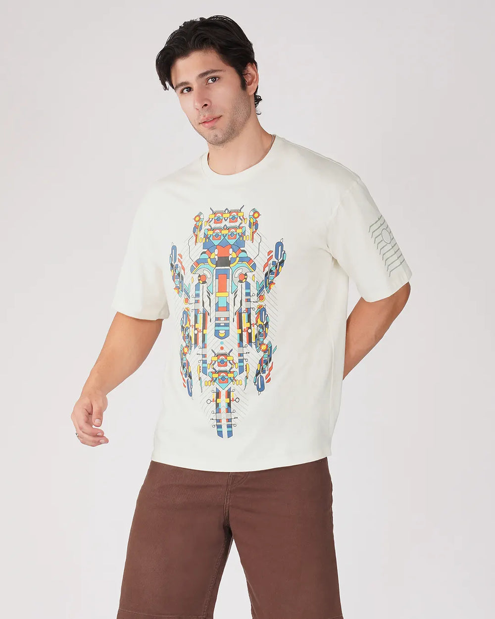 Man wearing a white t-shirt with a colorful robot design on a plain background