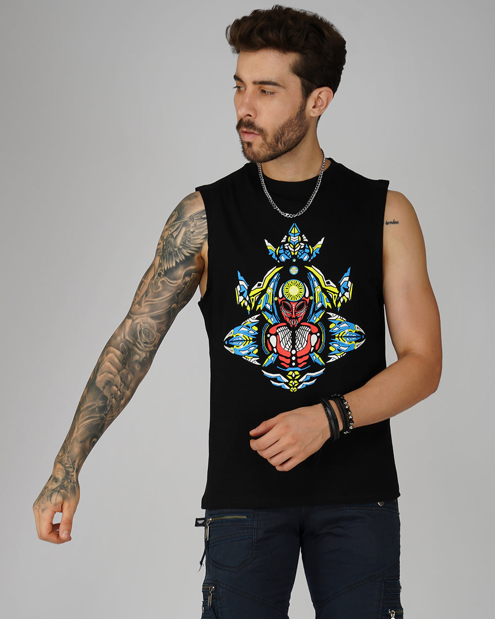 A male model wearing a black cotton tank top with a colorful, geometric pattern on the front.