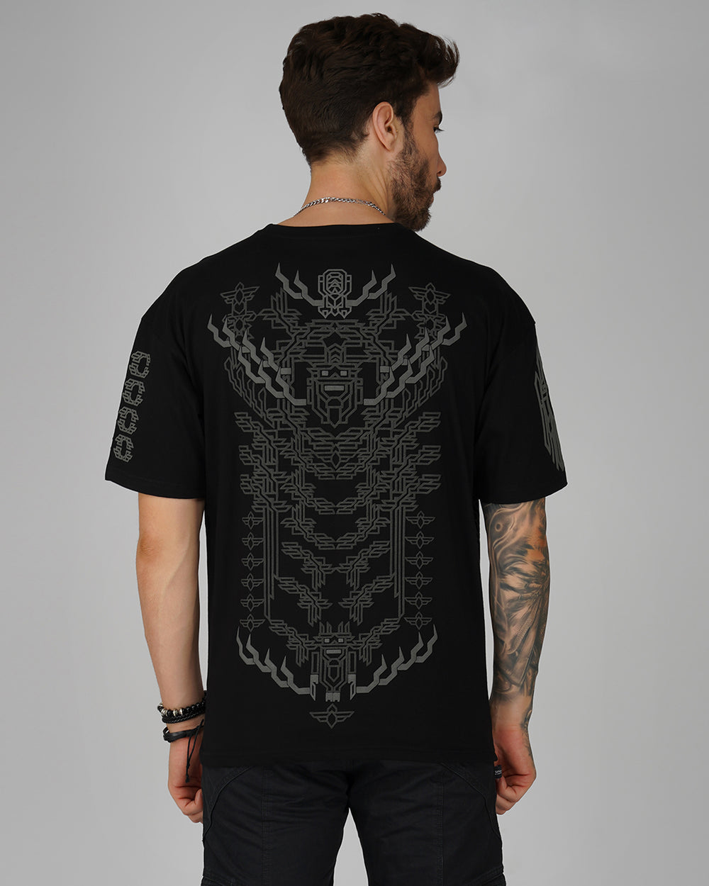A person wearing a black oversized cotton t-shirt with a 3D puff printed geometric design on the front.