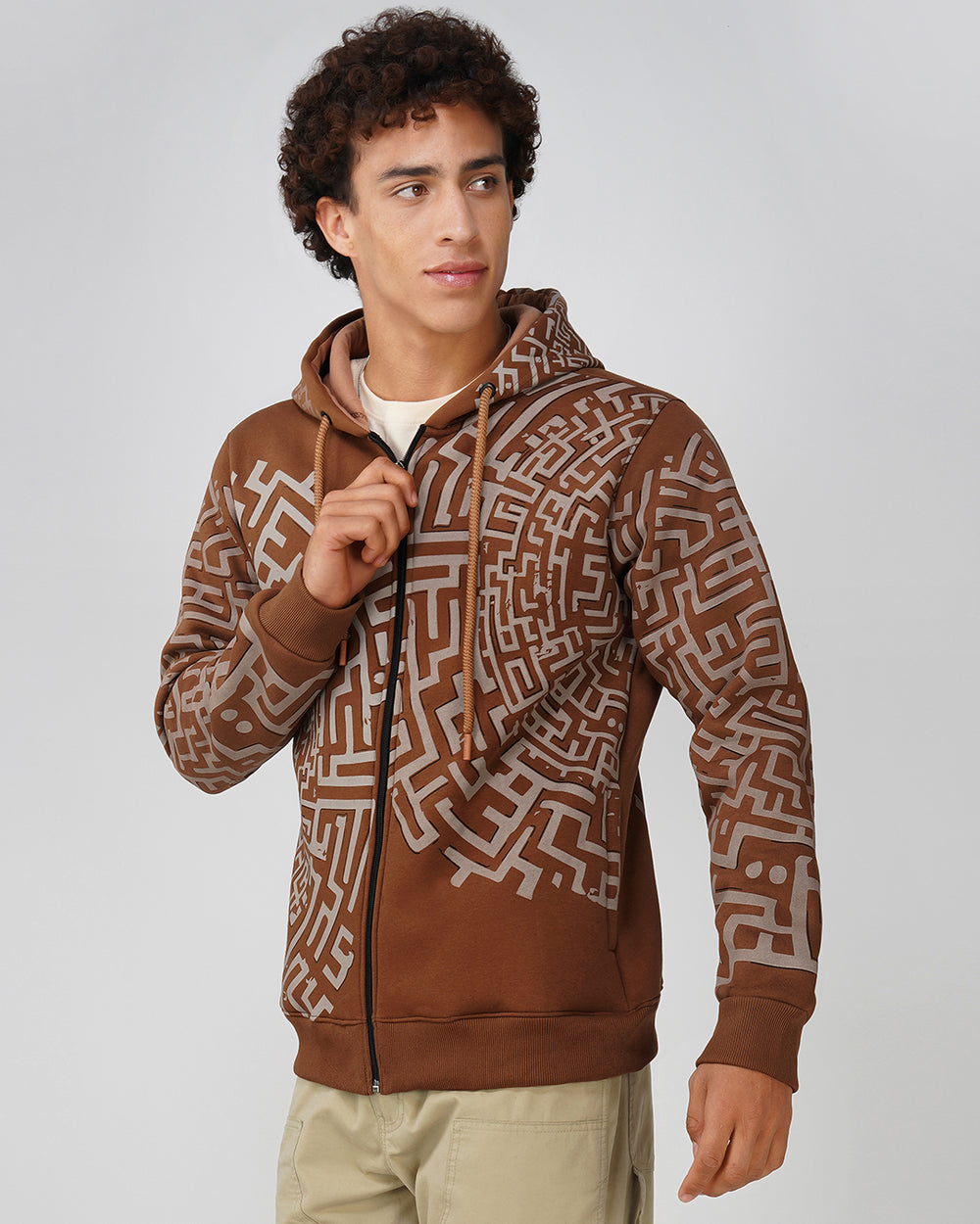 A man wearing a brown and beige geometric patterned zip-up cotton hoodie with a drawstring hood.