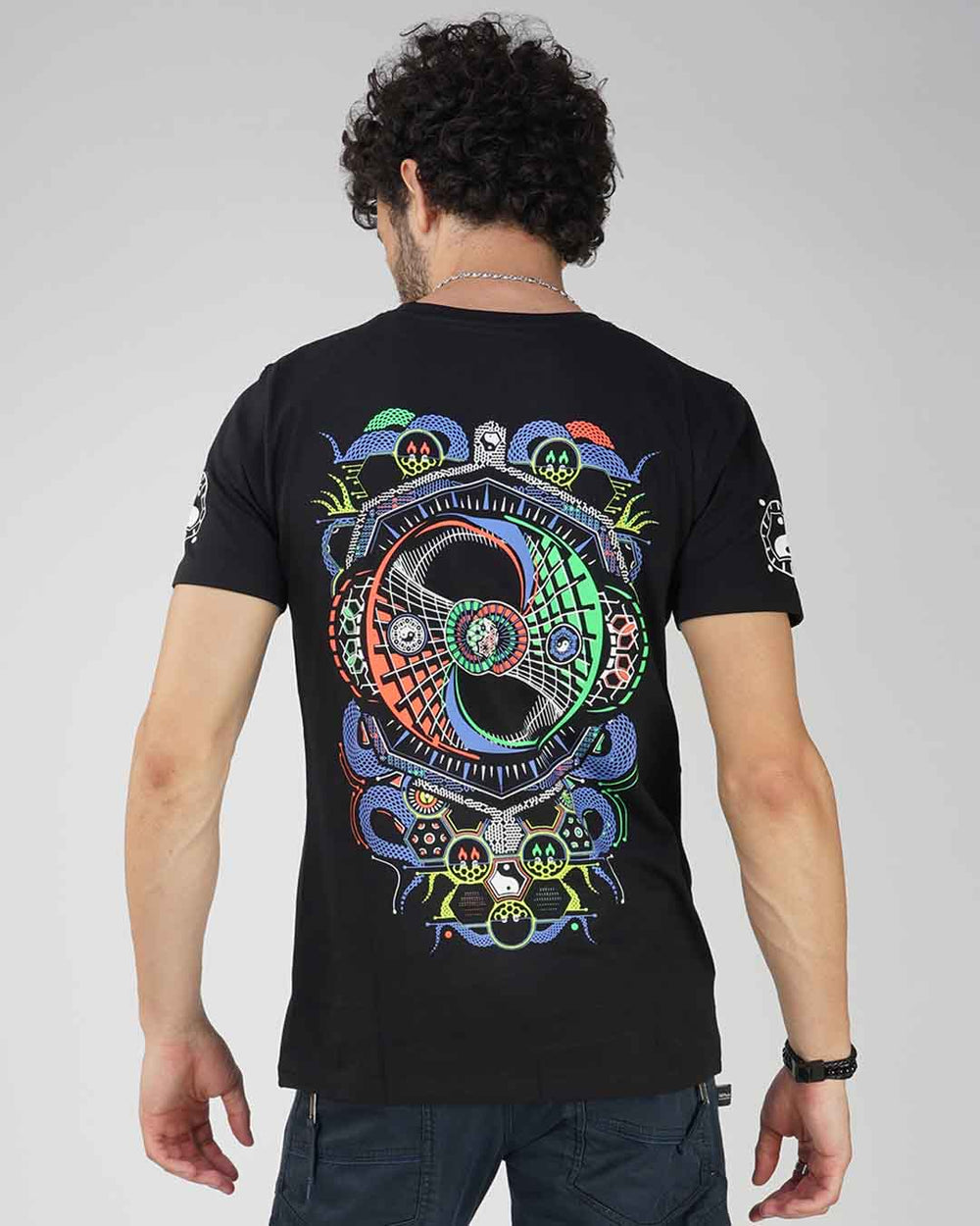 A male model wearing a black cotton t-shirt with a colorful, geometric pattern and a round neck.