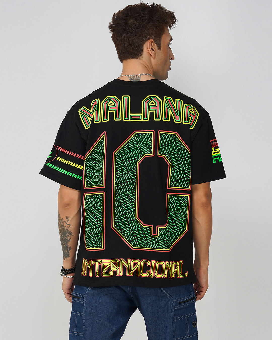 Man wearing a black t-shirt with colorful text and numbers on the back, standing against a plain background.