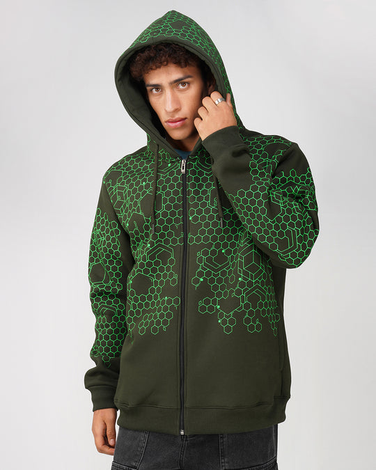 A person wearing a green zip-up hoodie with a geometric hexagon pattern, featuring a drawstring hood and ribbed cuffs.