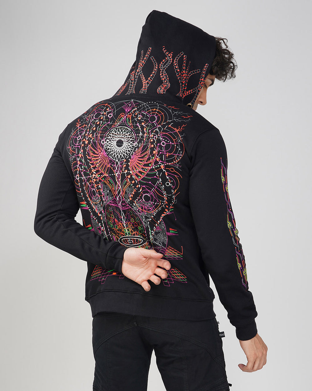 A person wearing a black cotton hoodie with UV light reactive plus glow in dark print, showcasing the hoodie's design on the back.