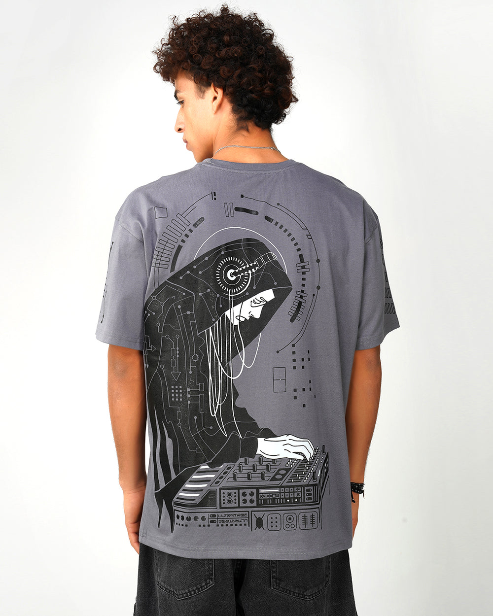 A person wearing a grey oversized cotton t-shirt with a black print of a figure playing a musical instrument and the text 'Monastik'.