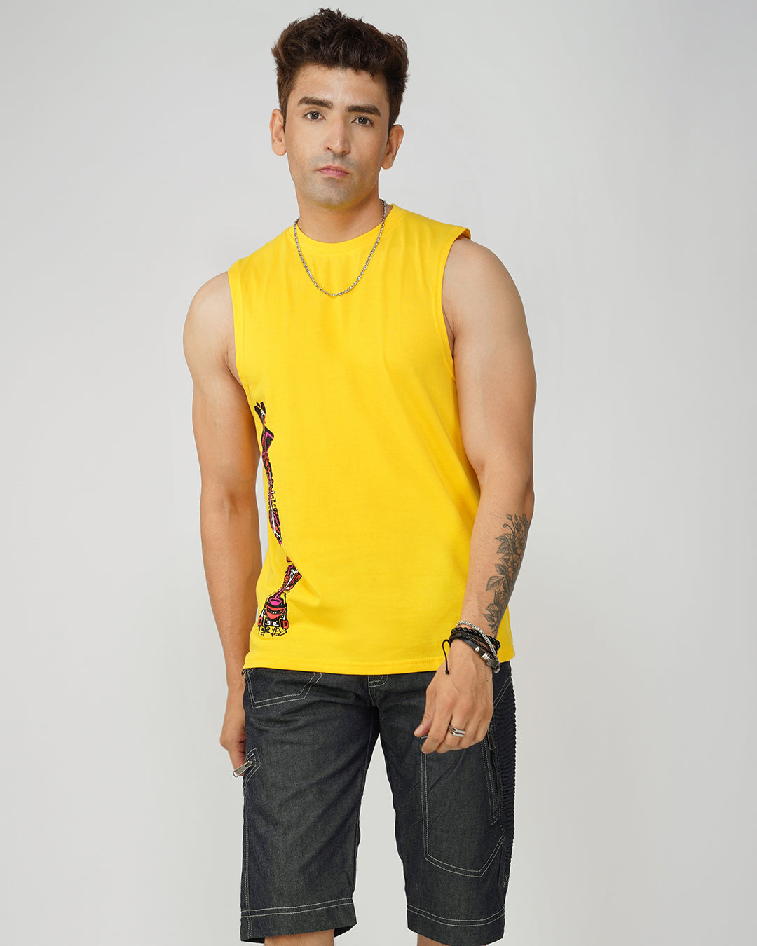 Man wearing a yellow sleeveless shirt with a graphic design on a plain background