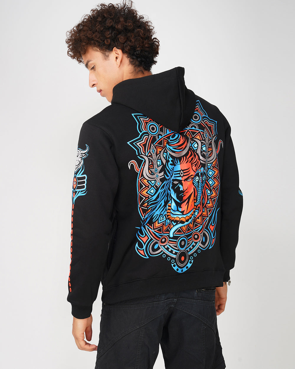 A person wearing a black hoodie with a geometric pattern featuring a prominent tiger design in blue and orange on the back.