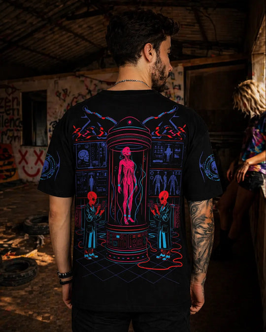 Person wearing a black ultra tribe uv light reactive t-shirt alien lab with a colorful graphic design in a dimly lit room.