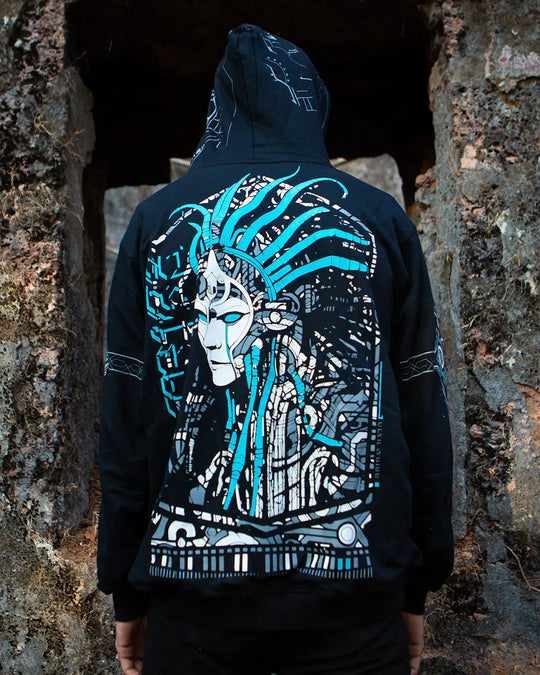 Person wearing a black hoodie with a detailed design on the back against a stone wall.