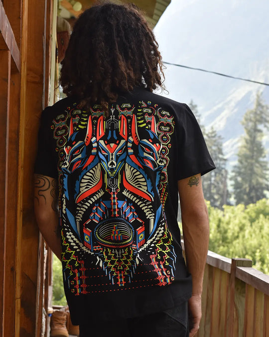 Person wearing a black t-shirt with a colorful abstract design outdoors.