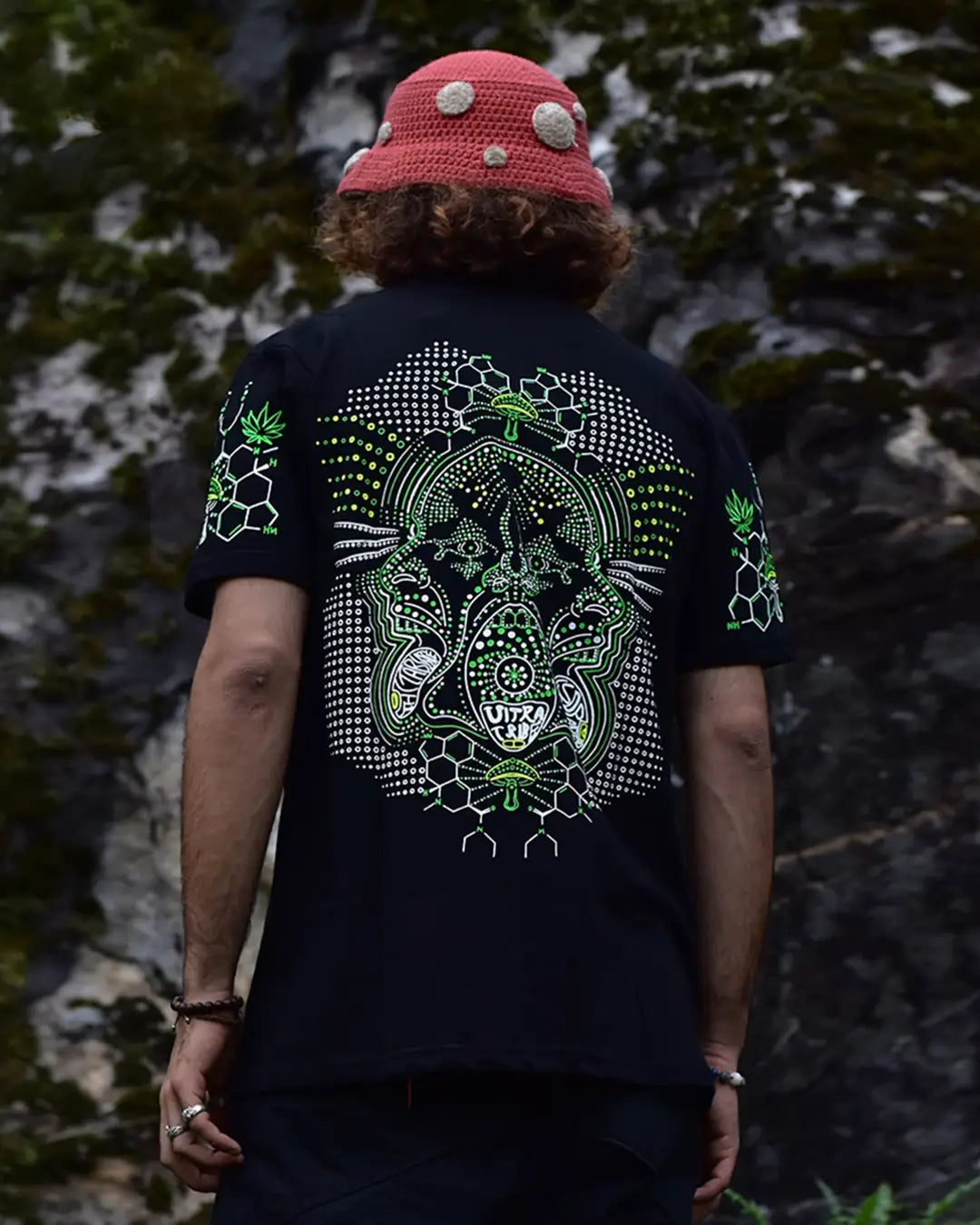 Person wearing a black t-shirt with a green and white design outdoors.