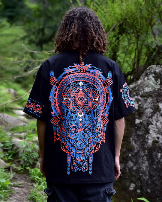 Person wearing a black t-shirt with a large blue and red geometric design outdoors.