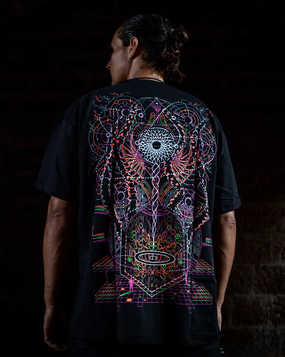 Person wearing a black t-shirt with a colorful abstract design on the back against a dark background