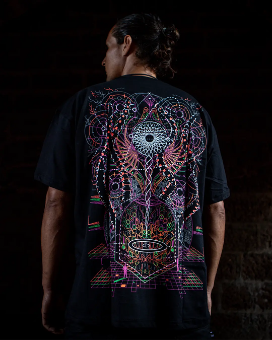 Person wearing a black t-shirt with a colorful abstract design on the back against a dark background