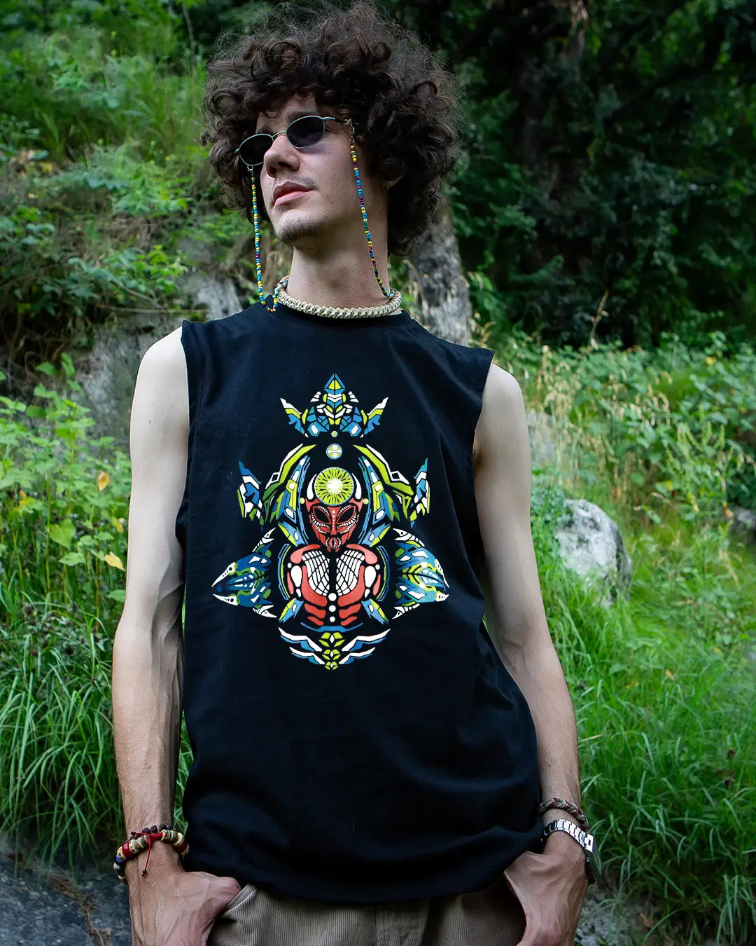 Person wearing a black sleeveless shirt with a colorful graphic design outdoors.