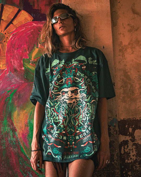 a women wearing a dark green t-shirt with mushroom psychedelic art print with a colorful graphic design against a textured wall.
