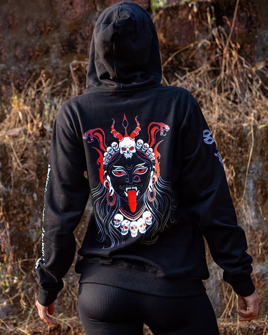 Person wearing a black hoodie with a colorful graphic mahakali design on the back with glow in dark print god kali artwork, standing in a natural setting.