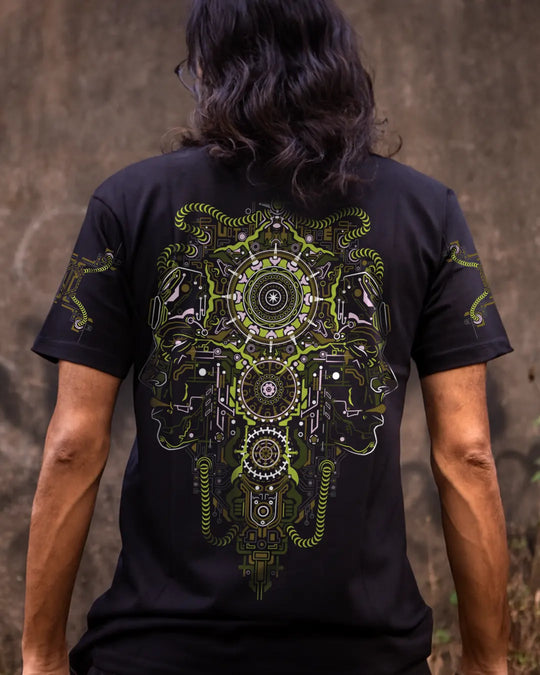 Person wearing a ultra tribe black Regular fit t-shirt with a detailed green and yellow psychedelic Mechanical Face  design UV Light Reactive Print on the back against a textured wall.