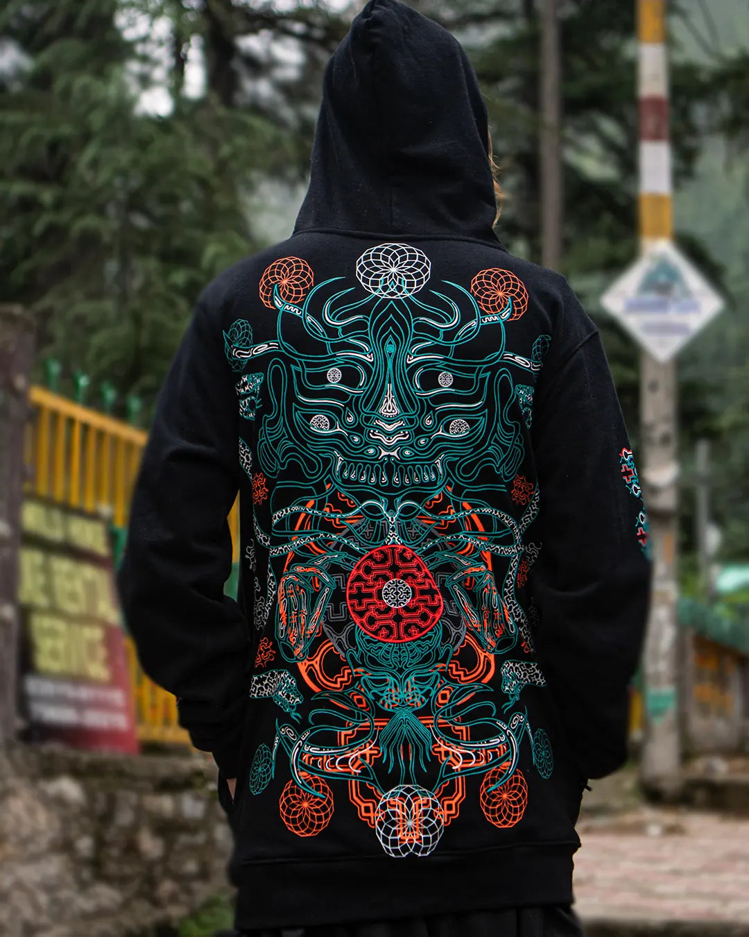 Person wearing a black hoodie with a colorful dragon design on the back, standing outdoors.