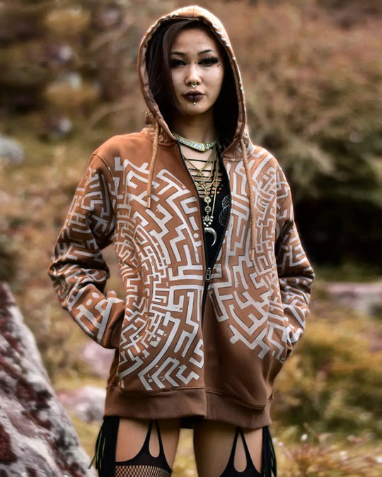 Person wearing a brown hoodie with geometric patterns in an outdoor setting