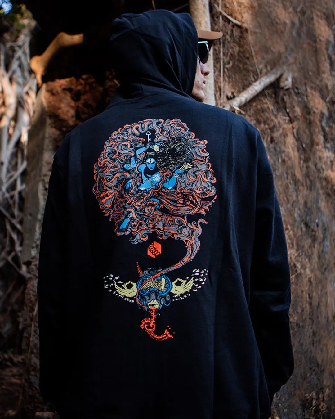 Person wearing a black Shiva Tandav Design Hoodie With UV Light reactive Print hoodie with colorful dragon design on the back, standing against a stone wall.
