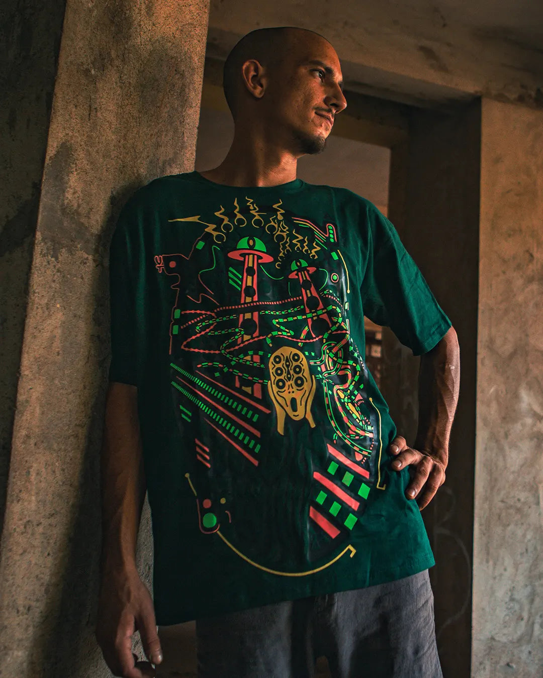 Man wearing a green t-shirt with a colorful graphic design of scream artwork  in an indoor setting tshirt by ultra tribe with UV Light reactive prints.