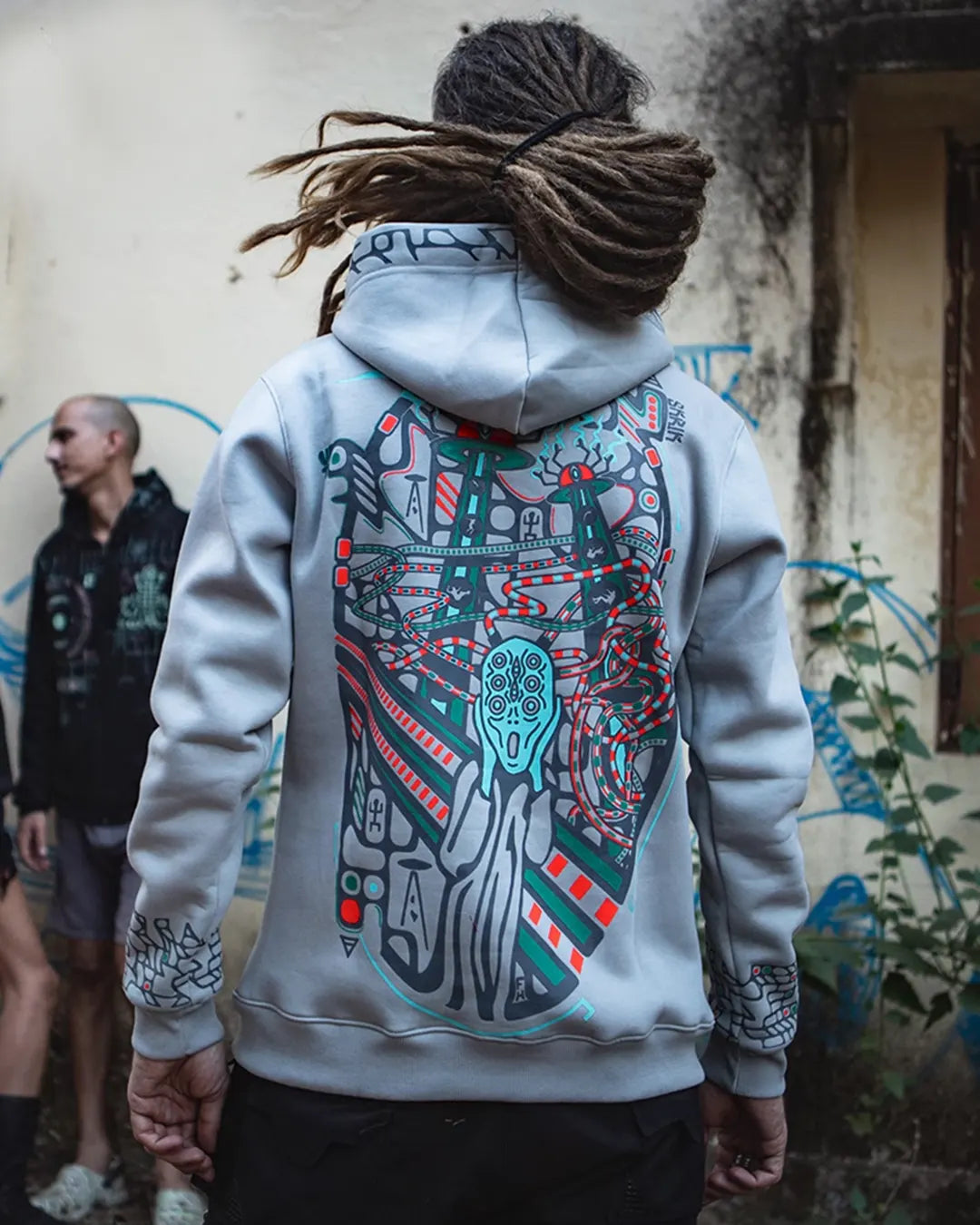 Person wearing a hoodie with a colorful design on the back, standing in an urban setting.