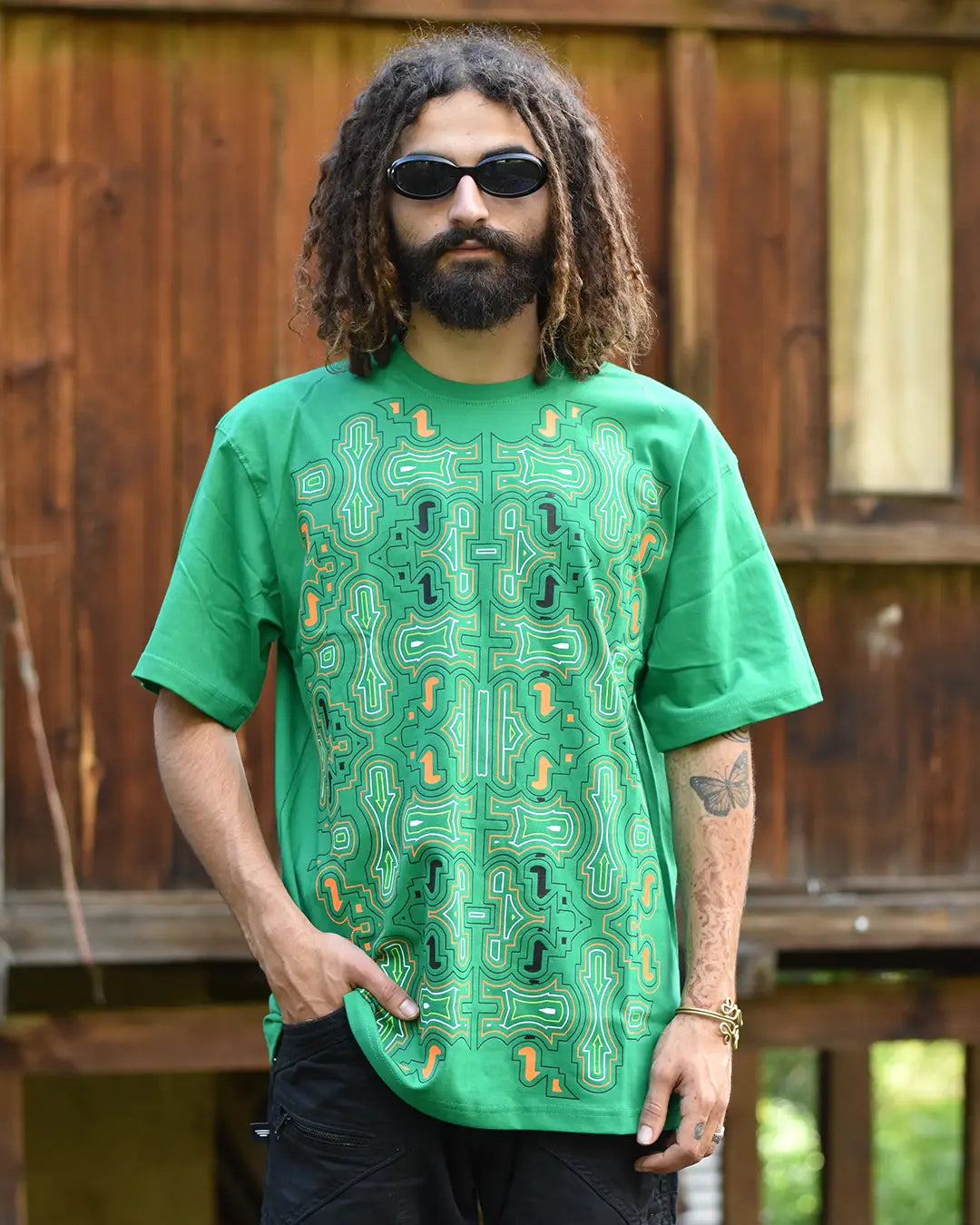 Man wearing a green graphic t-shirt with a wooden fence background