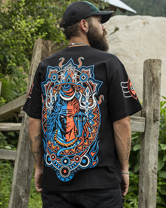 Person wearing a black oversized t-shirt with a colorful design Loard Shiva on the back, standing outdoors.