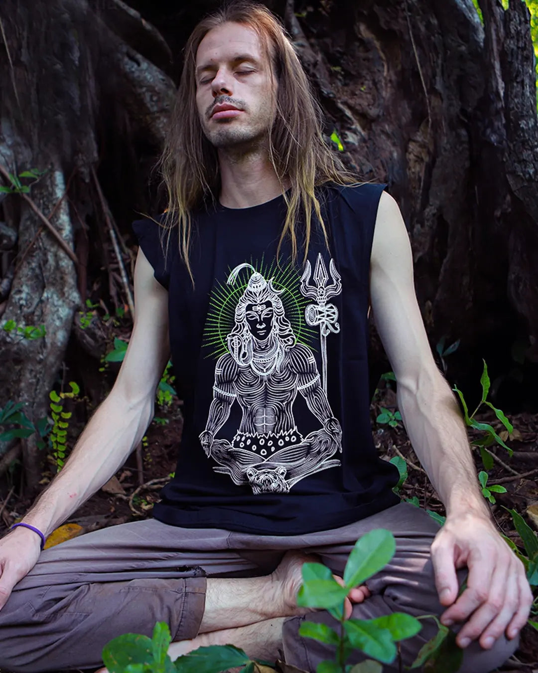 Person meditating outdoors wearing a black t-shirt with a white graphic Design of Shiva with glow in dark color ink. tank tees by ultra Tribe Apparels.