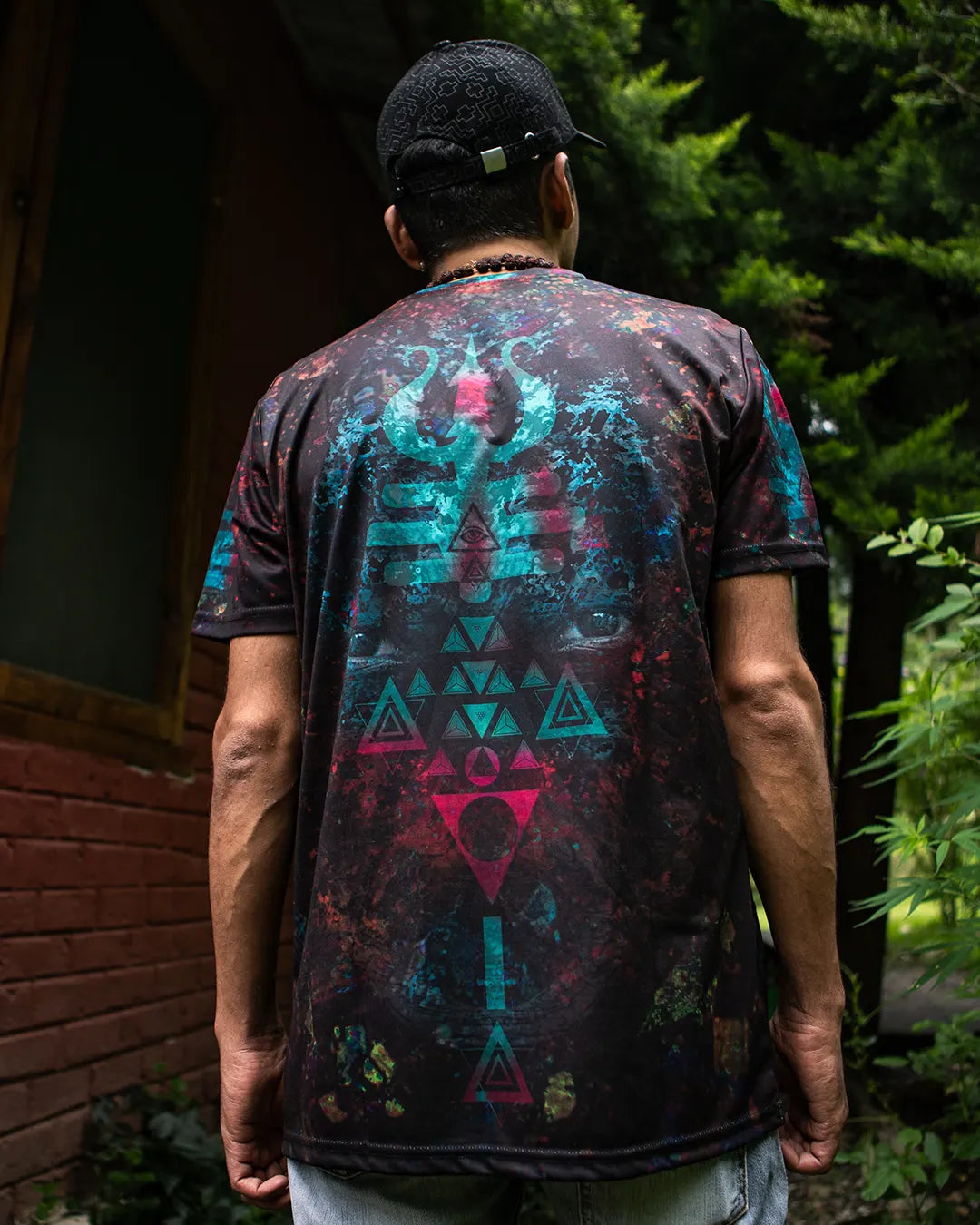 Person wearing a black t-shirt with colorful geometric patterns outdoors.