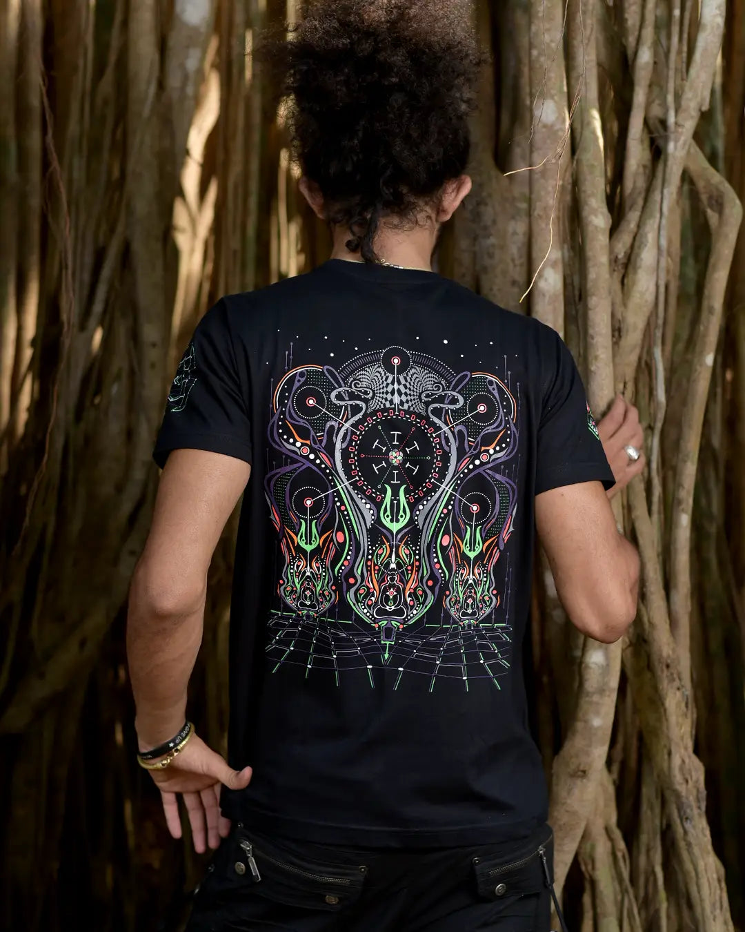 Person wearing a black t-shirt with a colorful design, standing against a natural background.