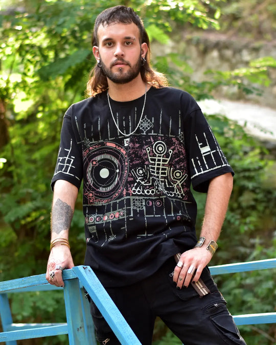 Man wearing a black graphic t-shirt outdoors with greenery in the background
