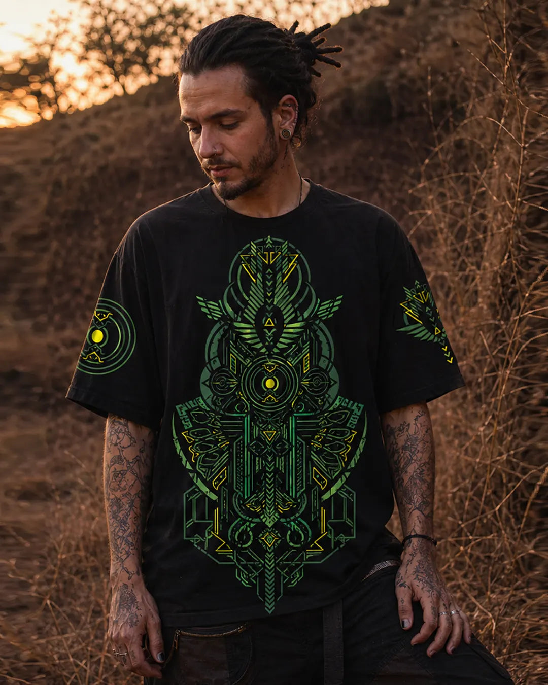 Man wearing a black t-shirt with green geometric design in a desert setting