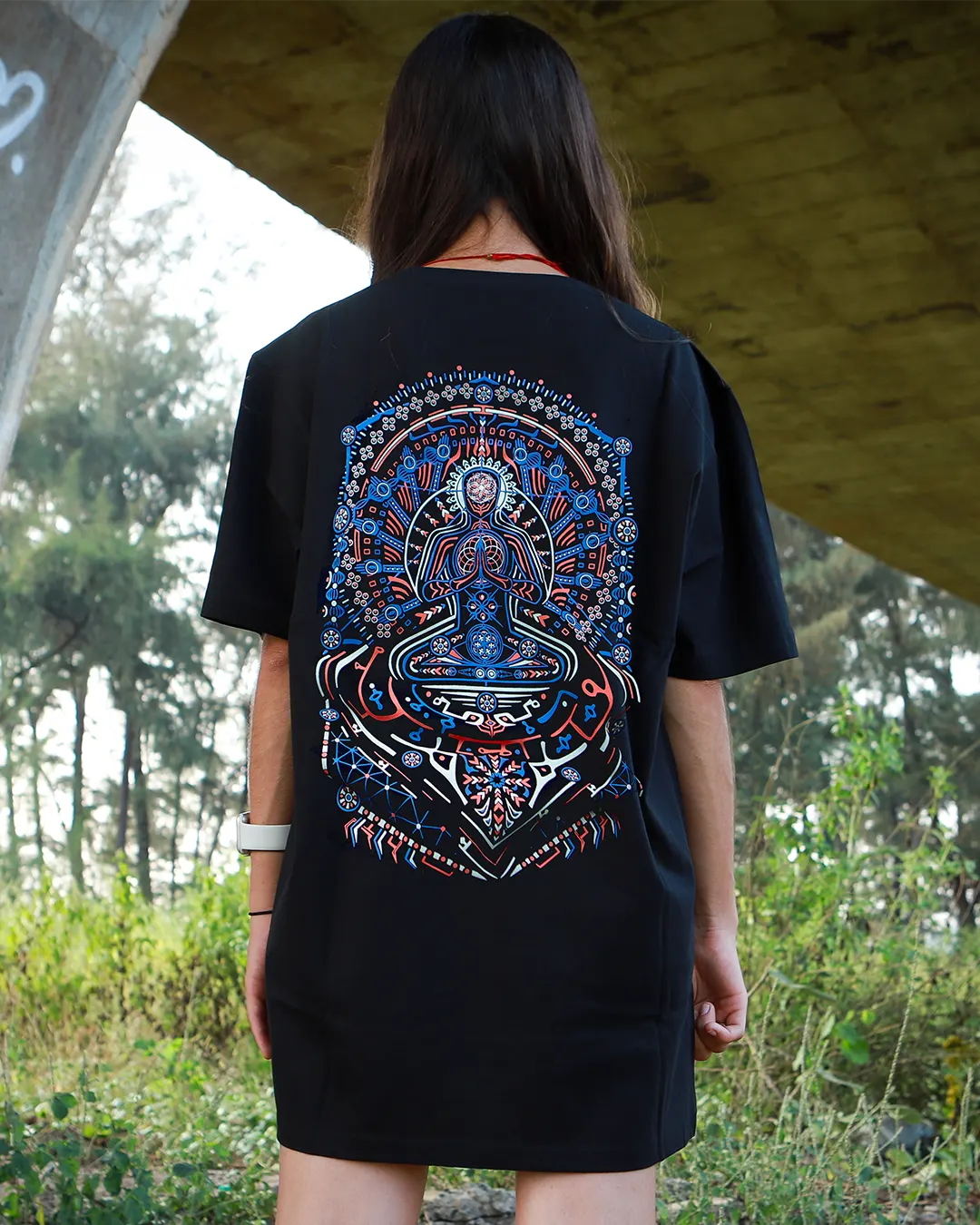Person wearing a black t-shirt with a colorful mandala design outdoors.