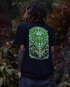 Person wearing a black uv light reactive and glow in dark t-shirt with a green and white graphic design, standing in a natural setting.