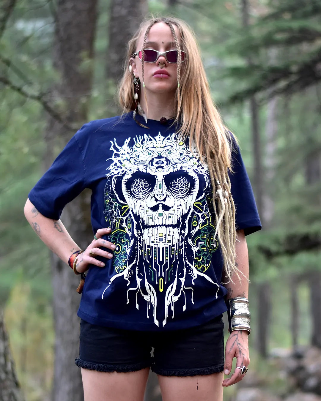 Person wearing a blue t-shirt with a skull design in a forest setting