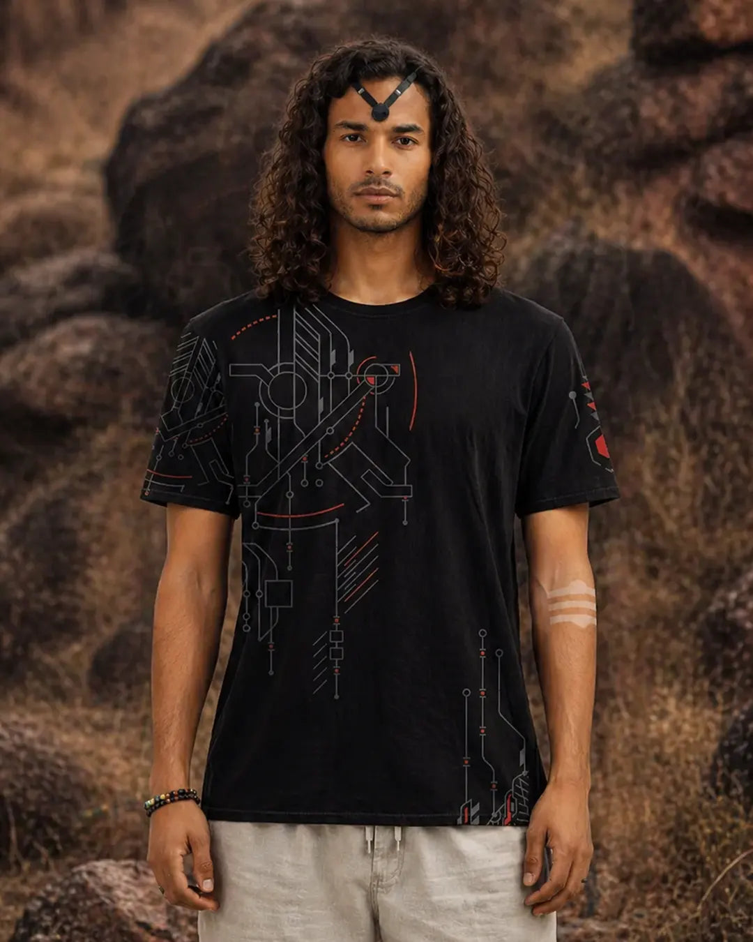 Person wearing a black t-shirt with geometric design against a rocky background