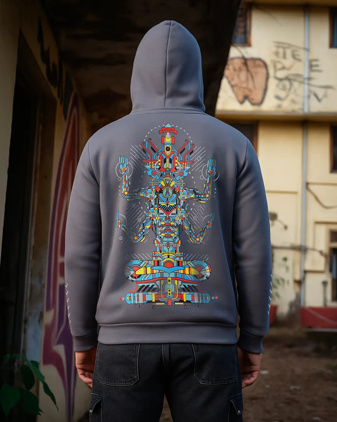 Person wearing a gray hoodie with a colorful back design in an urban setting.