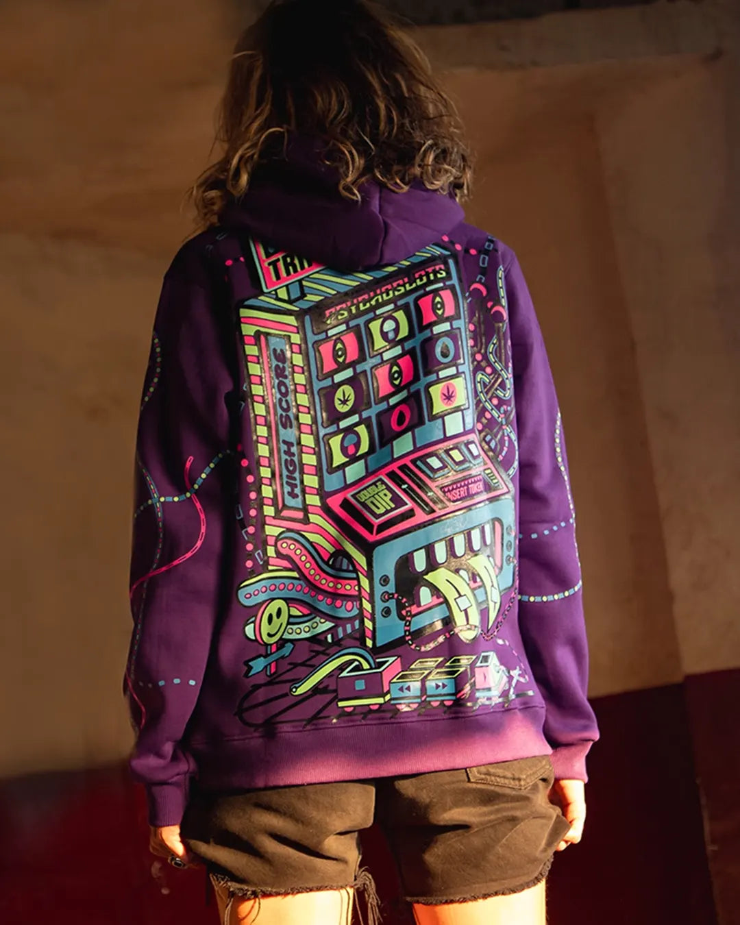 Person wearing a purple hoodie with a colorful graphic design on the back against a neutral background