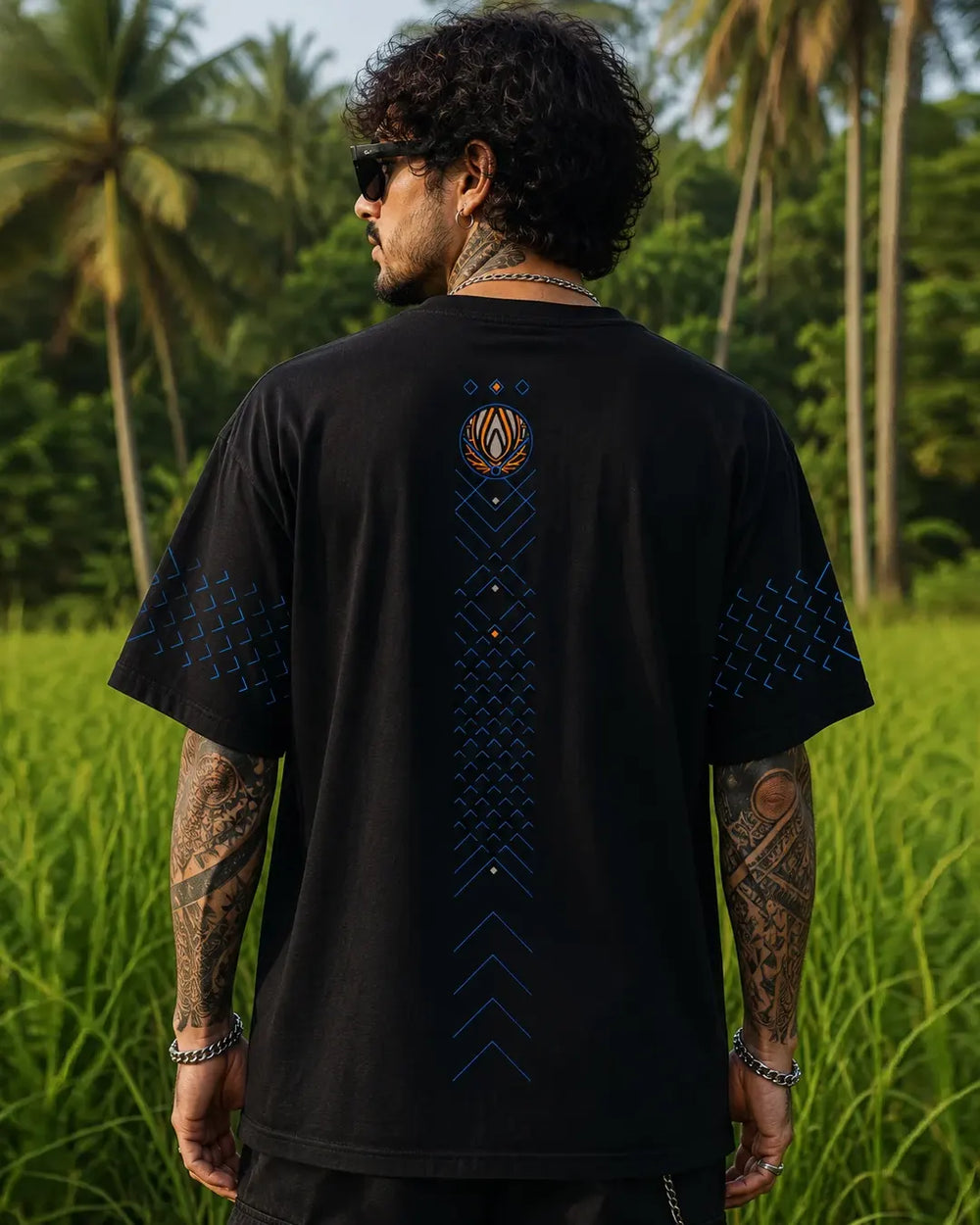 Back view of the Kanina black oversized T-shirt with a vertical blue geometric print and an orange emblem on the upper back.