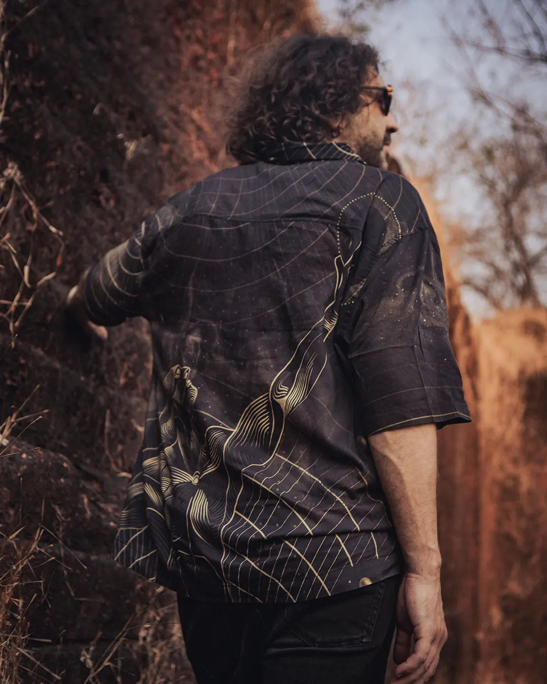 Person wearing a dark patterned shirt in a natural setting